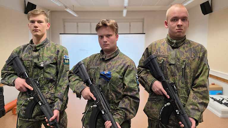 Viestintävarusmiehet Martti Pesonen, Kaarlo Valtonen ja Lauri Uimonen sisäampumasimulaattorissa.