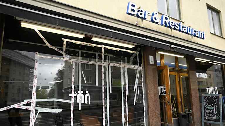 Teipillä korjatut baarin rikotut ikkunat.
