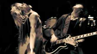 Bändin laulaja ja kitaristi esiintymislavalla. Kuva "epätarkka", kuvattavat liikkeessä.