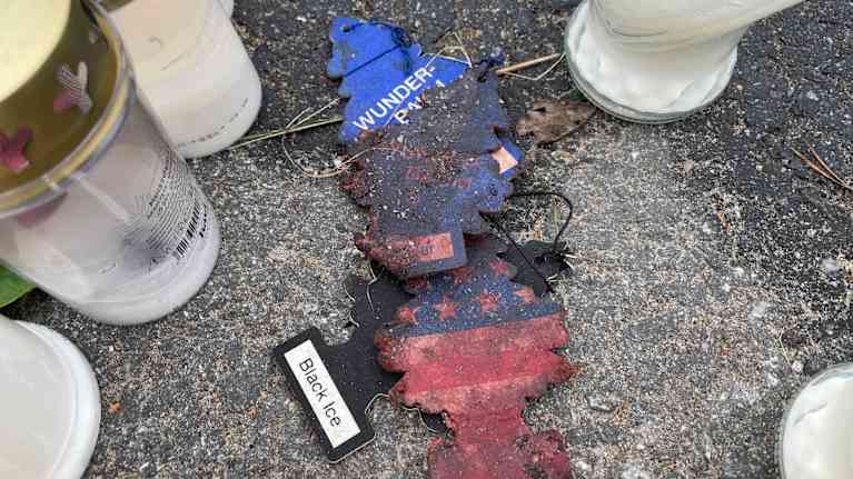 Asfaltilla on hautakynttilöitä ja niiden keskellä neljä osin palanutta Wunder Baum -ilmanraikastinta.