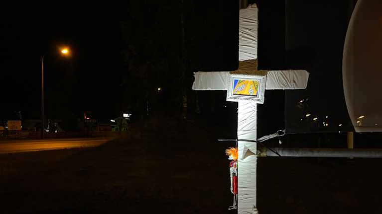 Valkoinen risti, johon on kiinnitetty kehystetty kuva ABC-tornista.