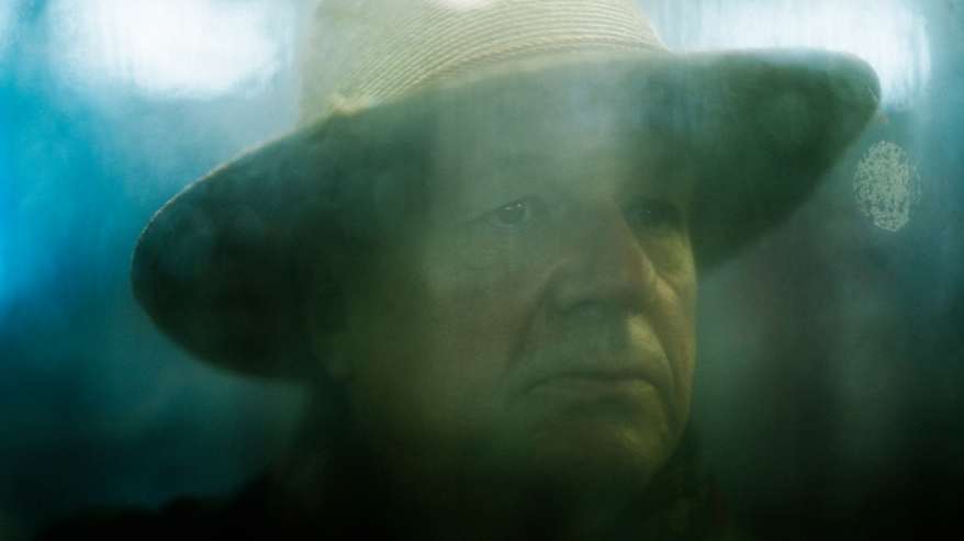 Mies seisoo hämärästi valaistussa, huurteen peittämässä sisätilassa yöllä.