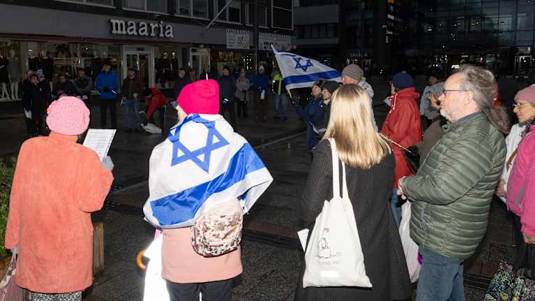 Joukko nielenosoittajia Oulussa, yhdellä hartioillaan Israelin lippu, toinen heiluttaa lippua taustalla.