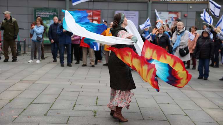 Nainen tanssii torilla mielenosoituksessa, taustalla heiluu Israelin lippuja.