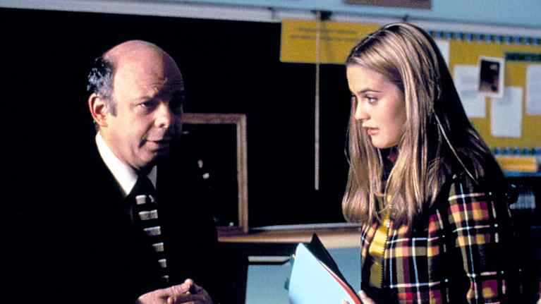 Kaksi Clueless-elokuvan hahmoa keskustelee luokkahuoneessa; opettaja näyttää mietteliäältä, pääosan esittäjä, lukiolaistyttö Cher pitelee kansiota.