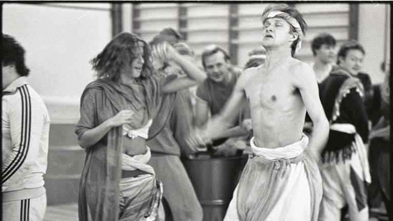 Ryhmä ihmisiä esiintyy ilmeisesti osana teatteriesitystä tai performanssia.