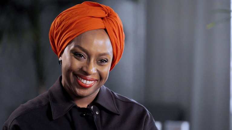 Henkilö hymyilee päässään punainen turbaani.