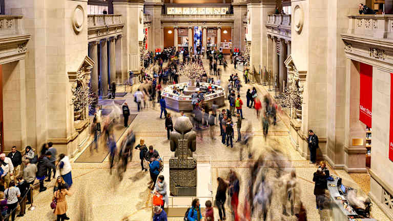 Kuvassa nähdään vilkas ja eläväinen Metropolitain-taidemuseo New Yorkissa, jossa ihmiset kuljeskelevat ja tutkivat taidekokoelmia.