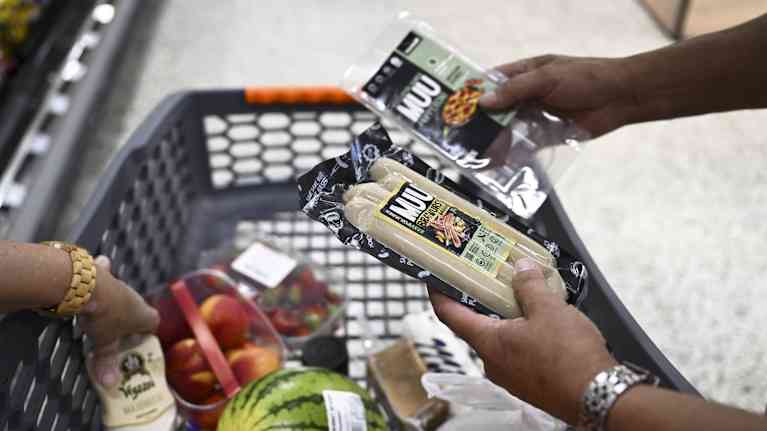 Asiakas tutkii kasvismakkara- ja kasvisleikepaketteja kaupassa.