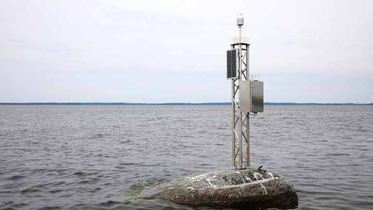 Mittauslaitetta muistuttava rakennelma kiven päällä keskellä järveä.