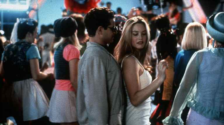 Clueless-elokuvan kohtaus, jossa kaksi nuorta tanssii lähekkäin vilkkaalla tanssilattialla, jossa ihmisiä nauttimassa musiikista ja tanssivat iloisesti.