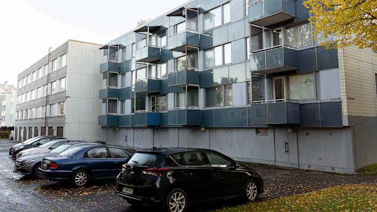 Matala kerrostalo syksyisessä kaupunkimaisemassa.