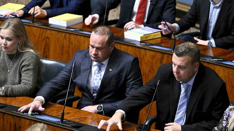  Mikko Polvinen ja Mikko Lunden painavat äänestysnappia eduskunnan istuntosalissa.