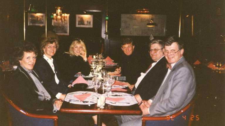 Ryhmä ihmisiä istuu ravintolapöydän äärellä.