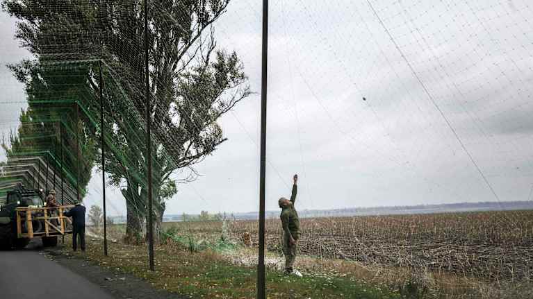 Henkilö asettelee tien reunassa jättimäistä verkkoa.