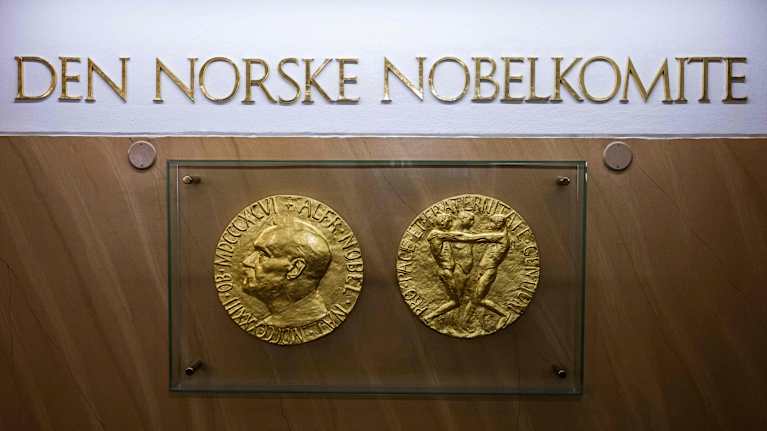 Nobelin rauhanpalkinto -mitalin etu- ja kääntöpuolen jäljennökset.