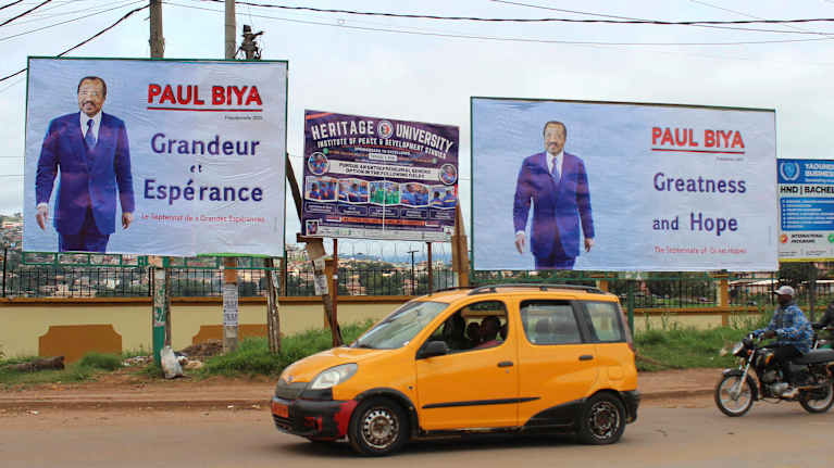 Kahdessa tien varrella olevassa mainostaulussa on sama mies sinisessä puvussa.