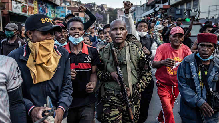 Madagaskarin armeijan sotilas mielenosoittajien ympäröimänä.