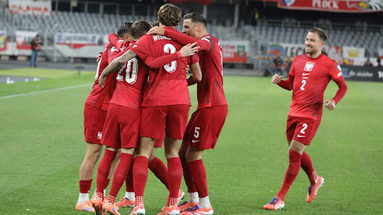 Puolan jalkapallomaajoukkueen pelaajat juhlivat maalia kentällä.