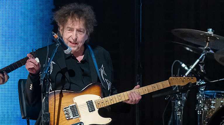 Dylan esiintyykitaran kanssa lavalla.