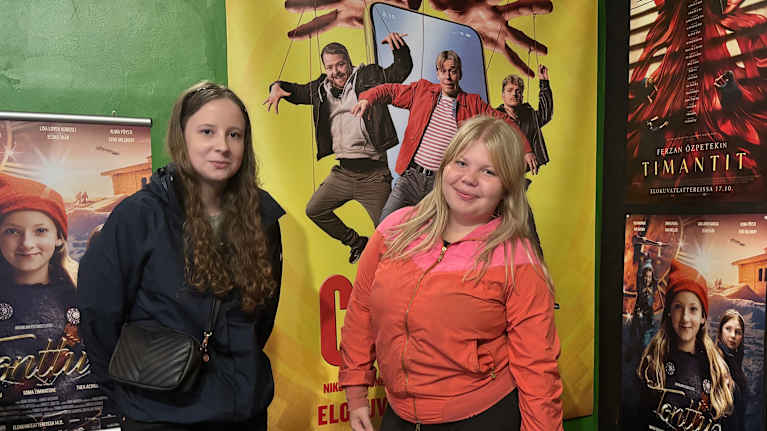 Kaksi nuorta elokuvajulisteen edessä.