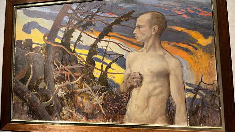 Mies seisoo ylävartalo paljaana paksujen oksien vieressä.