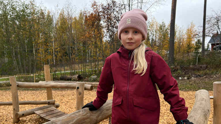 Tyttö seisoo leikkikentällä kiipeilytelineessä.