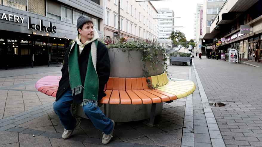 Valokuvaaja Antti Sepponen istuu penkillä Lahden Lanunaukiolla.