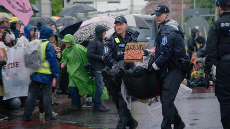 Kaksi poliisia kantaa mielenosoittajaa.