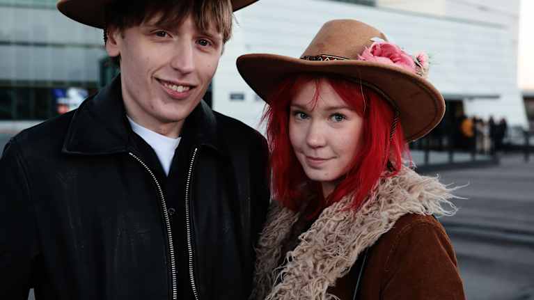 Pariskunnalla ruskeat hatut, joissa on kukkakoristeita. 