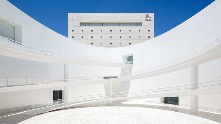 CajaGranada kulttuurikeskus sisäpihalta kuvattuna. Valkoiset, kaarevat seinät ja spiraalimaiset rampit. Takana suorakaiteen muotoinen korkea rakennus.