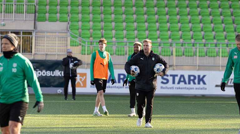 KTP:n päävalmentaja Ossi Virta kävelemässä pallot käsissä harjoituksissa.