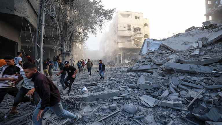 Ihmiset juoksevat raunioiden keskellä.