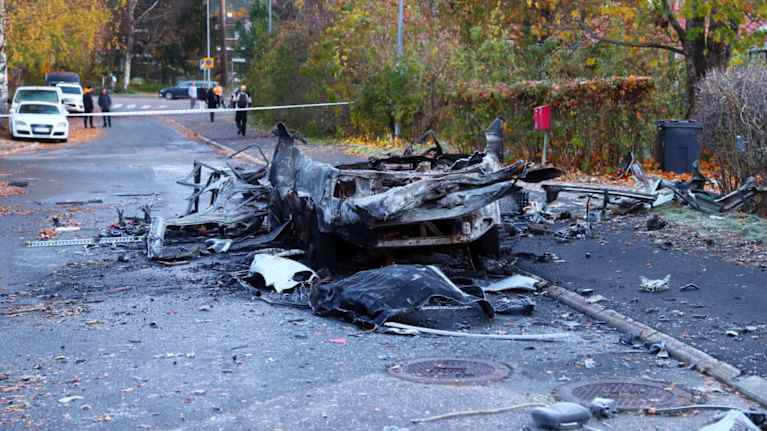 Räjähdyksessä tuhoutunut auto kadulla.