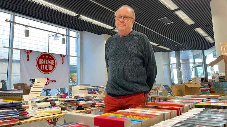 Mies seisoo keskellä kirjakauppaa.