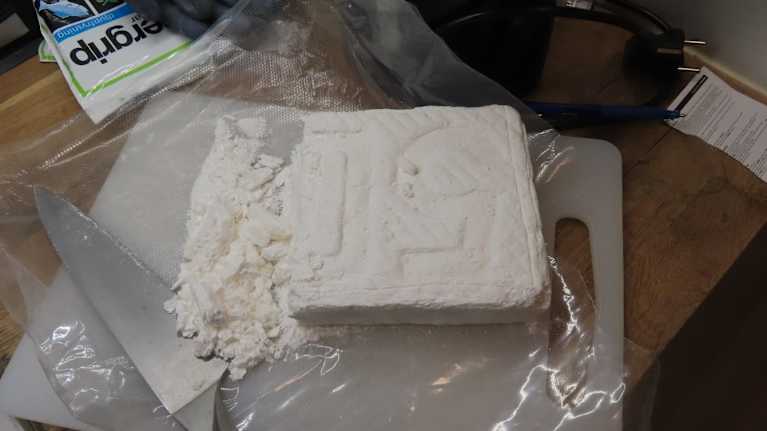 Pöydällä leikkuulaudan päällä on suuri määrä kokaiinia ja veitsi, jolla sitä on leikattu.
