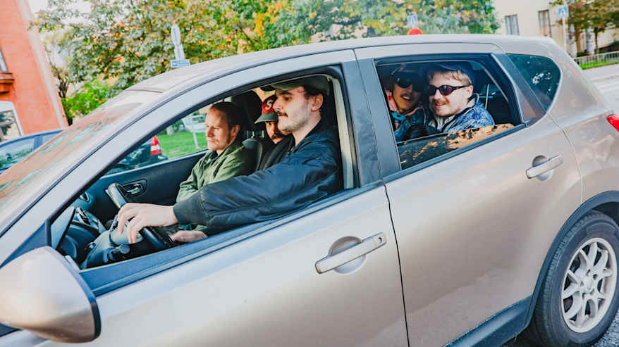 Good Boys istuu beigen auton kyydissä. Kuskina on Roy Kaarla.