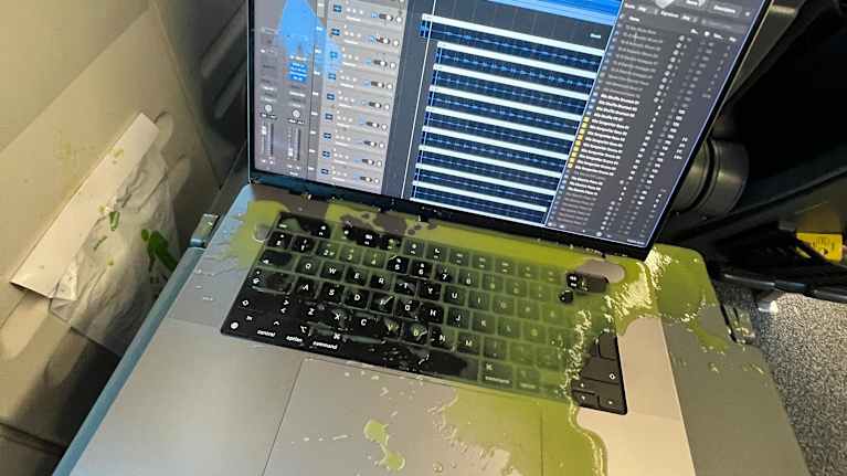Käynnissä olevan kannettavan tietokoneen päälle on kaatunut nestemäinen vihersmoothie.