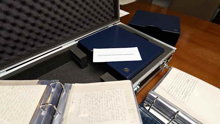 Pöydällä on auki kansioita, joissa on kirjeitä.