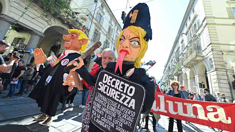 Mielenosoituksessa Torinossa kulkueen osallistujat kantavat suuria poliittisia karikatyyrihahmoja Giorgio Melonista ja Donald Trumpista.