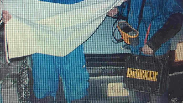 Kaksi nuorta seisoo auton edessä sähkölaitteiden ja kartan kanssa. 