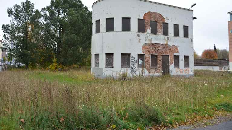 Ränsistynyt rakennus, jonka edustalla kasvaa rikkaruohoja.