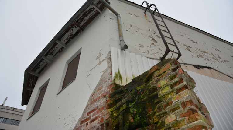 Ränsistyneen rakennuksen nurkkaus, josta rappaus on tippunut.