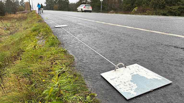 Kaksi poliisia tekee mittauksia tien reunassa.