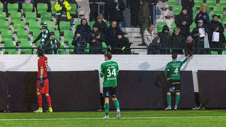 KTP:n kannattajat istuvat katsomossa sateisella säällä.