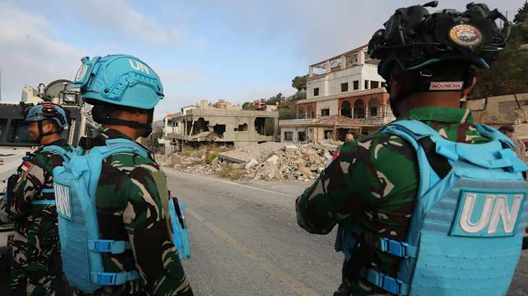 Kaksi Unifil-sotilasta tarkkailemassa tilannetta tuhoutuneiden rakennusten edessä.