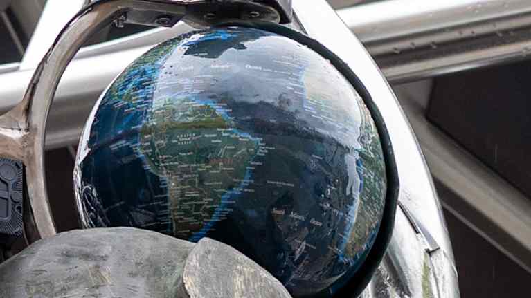 Metallisen runkon keskellä näkyy karttapallo.