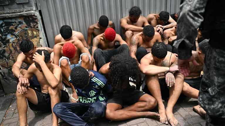 Maassa istuu joukko Brasilian poliisin pidättämiä epäiltyjä rikollisia.