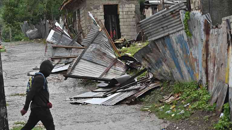 Mies kävelee tuhoutuneen talon ohi. 