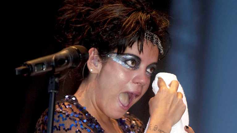 Lily Allen  pyyhkii pyyhkellä kasvojaan esiintymislavalla.